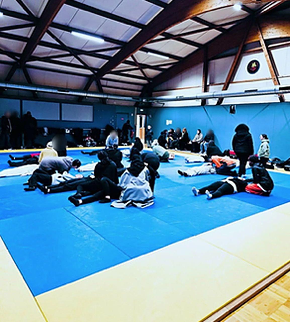 Atelier de self-défense dans un gymnase : des jeunes filles s'entraînent sur les tapis.