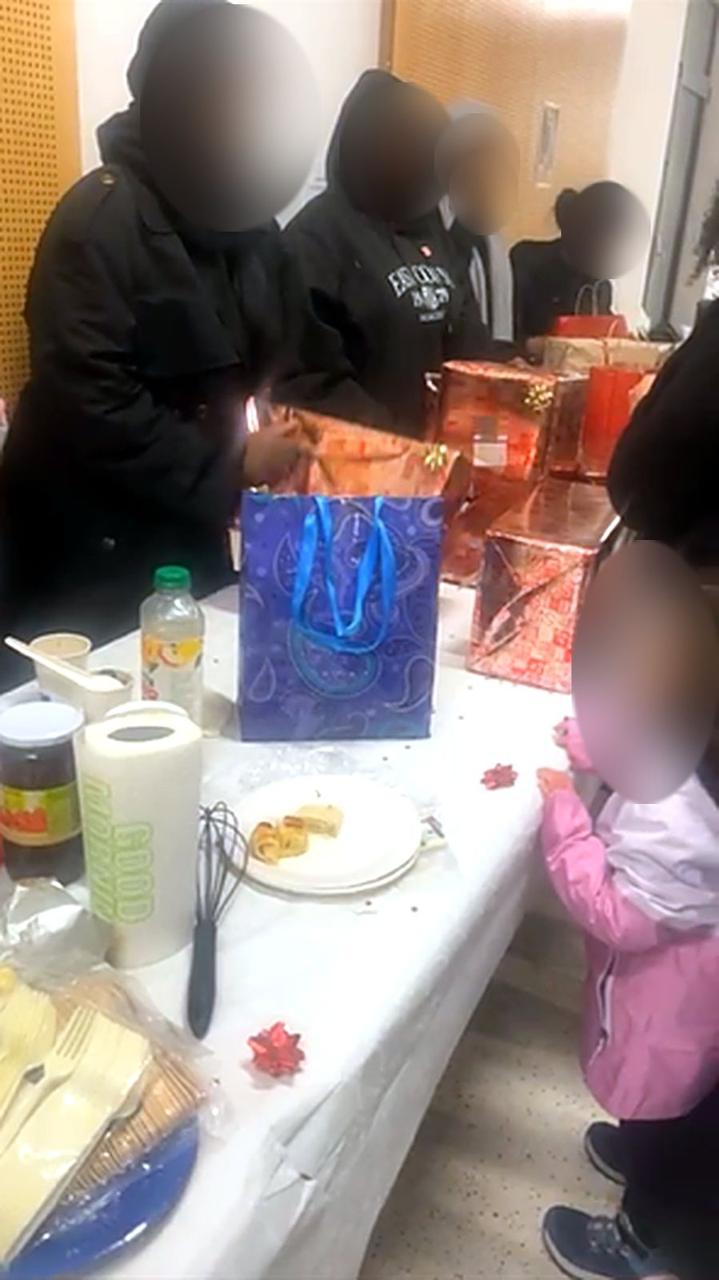 Des jeunes distribuent des cadeaux de Noël à des enfants, visages floutés.