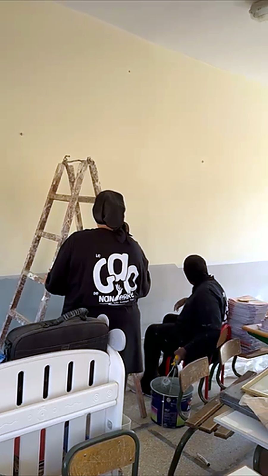 Des jeunes du GAO, de dos, repeignent une salle de classe au Maroc.