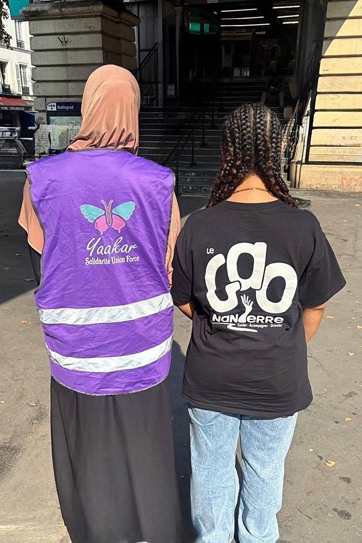 Une bénévole de l'association YAAKAR et une jeune avec le t-shirt du GAO, de dos.